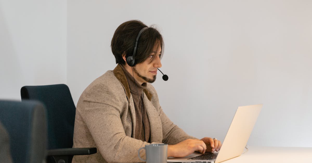 Man with headset typing on laptop in a modern office setting, providing customer support.
